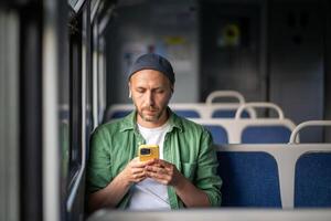 Thoughtful commuter listen to audio content on smartphone via earbuds, sit in train on way to work photo