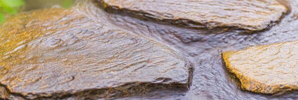 Flowing water over natural stones in a serene outdoor environment photo