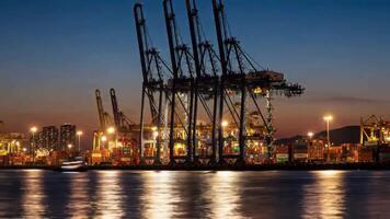Nighttime Panorama of a Bustling Container Port with Illuminated Cranes and Cargo Ships Reflecting on Calm Waters video