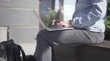 Self employed woman concept. Mature woman on bench with laptop. Remote work in park. Working from a distance in social isolation. Middle age woman tapping keyboard computer near electric scooter. video