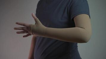 Woman in a studio demonstrates a medical compression sleeve for arm support. Designed for thrombosis, lymphedema, and circulation issues, it aids recovery, reduces swelling, and improves blood flow. video
