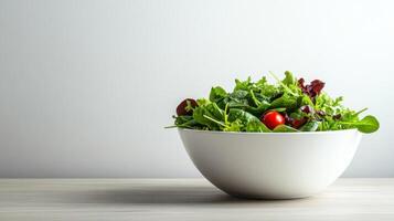 White bowl filled with fresh green salad including lettuce cucumbers and tomatoes on wooden table photo