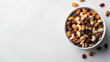 Bowl filled with assorted nuts and dried fruits on a white surface photo