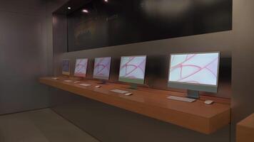 September 16, 2022, Munich, Germany. Apple Store in Munchen. Display stand with iMac computers on wooden tables in stylish interior with black walls and modern lighting. Sleek and tech-savvy design video