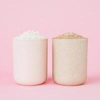 Two Speckled Ceramic Cups Filled with White and Brown Powders on Pink Base photo