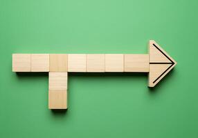 A wooden arrow pointing to the right on a green background photo