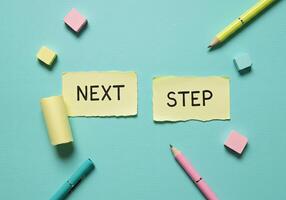 Next step and step concept with colored sticky notes and pencils on blue background photo