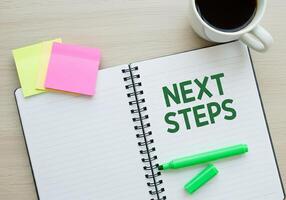 Next steps on notebook with pen and coffee cup photo