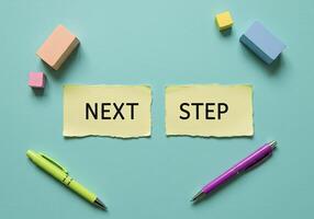 Next step concept with colored sticky notes and pens on blue background photo