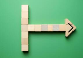 Wooden blocks with arrow pointing to the right on green background photo