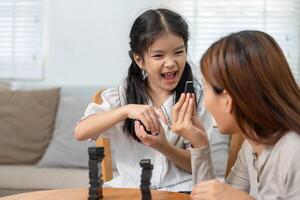 Playfulness and Family Dynamics. A child delights in playing a game, showcasing bonding and laughter with her mother. photo