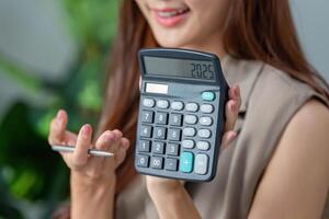 Calculator Insights and Financial Planning. A woman revealing her calculator displaying a financial figure. photo