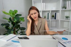 Stress Management and Problem Solving. A woman experiencing stress while evaluating financial reports at her desk. photo