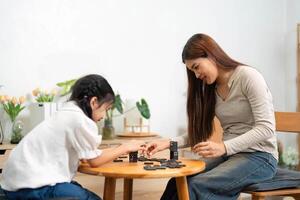 calidad hora y divertido aprendiendo. un niña enfocado en un tablero juego mientras jugando con su madre, creando perdurable recuerdos juntos. foto