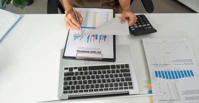 Financial Organization and Data Review. An individual sorting through financial reports and documentation on a desktop. photo