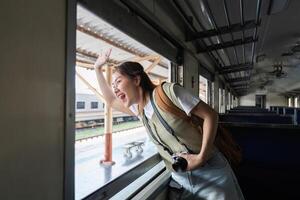 Dynamic Travel and Enthusiasm. A woman waves goodbye from the window of a train, embracing the joy of travel. photo