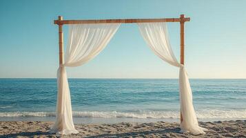 Tropical Seaside Ceremony Setup with Simple Bamboo Wedding Arch and Sheer Fabric Curtains Blowing in the Ocean Breeze photo