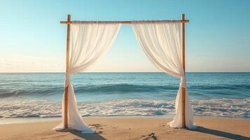 Romantic Beach Wedding Backdrop with Minimalist Bamboo Arch and Flowing White Drapes at Sunset on a Tropical Seashore photo