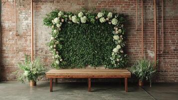 Elegant Rustic Wedding Backdrop with Luxurious Green Leaf Wall Installation Adorned with White Hydrangeas and Blush Roses Against Industrial Brick Wall with Wooden Bench photo