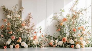 Stylish Floral Ceremony Arch with Soft Blush, Cream, and Apricot Flowers Framing a Clean Modern White Wall for Wedding or Event Decor photo