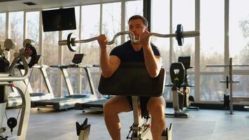 Man training biceps with barbell in gym video