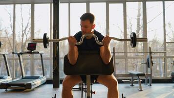 Focused man doing preacher curls in gym video