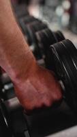 Close-up view of a man s hand grabbing a dumbbell from a weight rack in a modern gym video