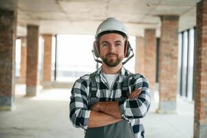 Portrait, in hard hat. Construction worker in uniform in empty unfinished room photo