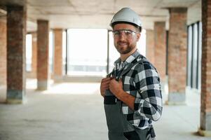 Positive ,,smiling construction worker in uniform in empty unfinished room photo