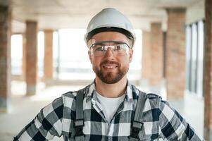 Positive, smiling construction worker in uniform in empty unfinished room photo