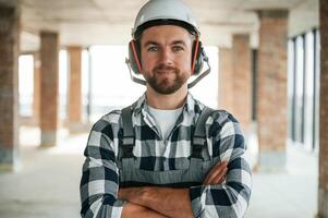 Portrait, in hard hat... Construction worker in uniform in empty unfinished room photo