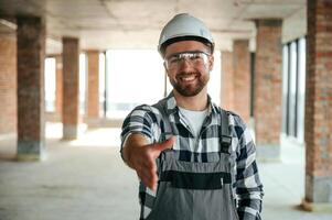 Positive smiling ,construction worker in uniform in empty unfinished room photo