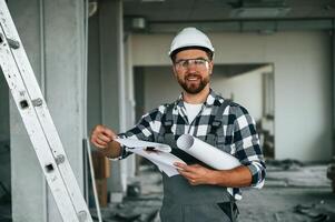 Manager, is with plan in hands. Repairman in uniform is in the unfinished building photo