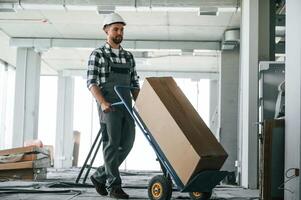 Transporting long paper box,.. Construction worker in uniform in empty unfinished room photo