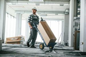 Transporting long ,paper, box.. Construction worker in uniform in empty unfinished room photo