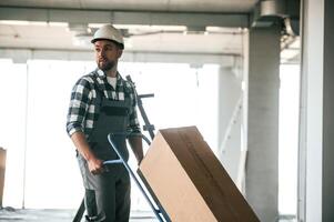 Walking and, transporting the paper box. Repairman in uniform is in the unfinished building photo