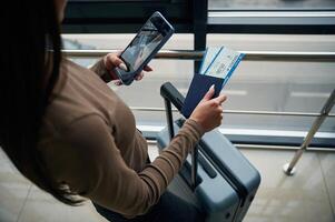 Holding smartphone. Close up ,view of female traveler in airport hall with tickets photo