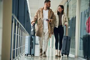 Front view, walking. Couple are ,in ,the ,airport hall together photo