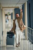 Running, late, for ,flight, with tickets in hand. Young handsome man in the airport photo