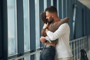 Preparing for long flight, embracing ,each other. Couple are in the airport hall together photo