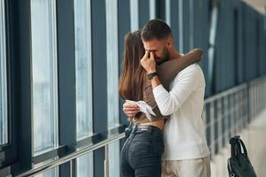 Preparing for, long flight, embracing each other. Couple are in the airport hall together photo