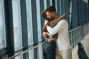 Preparing, for long flight, embracing each other. Couple are in the airport hall together photo