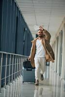 Running,, late for flight, with tickets in hand. Young handsome man in the airport photo