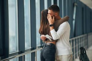 Man, is crying, embracing, farewell. Couple are in the airport hall together photo