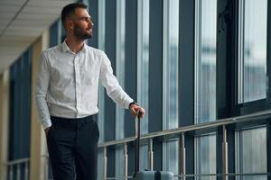 Standing, looking ,,through the windows. Young handsome man in the airport photo