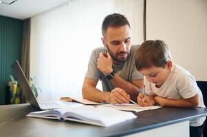 Doing homework. Father and son, are, at home by the table photo