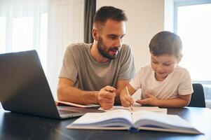 Doing homework., Father ,and son are at home by the table photo