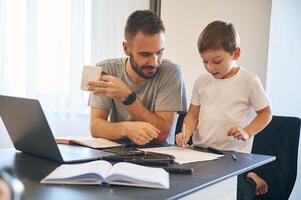 Doing homework... Father and son are at home by the table photo