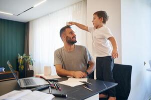 Father, and son are at home by the table photo