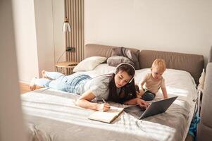 On the comfortable bed,. Mother with her little son is at home in domestic room photo